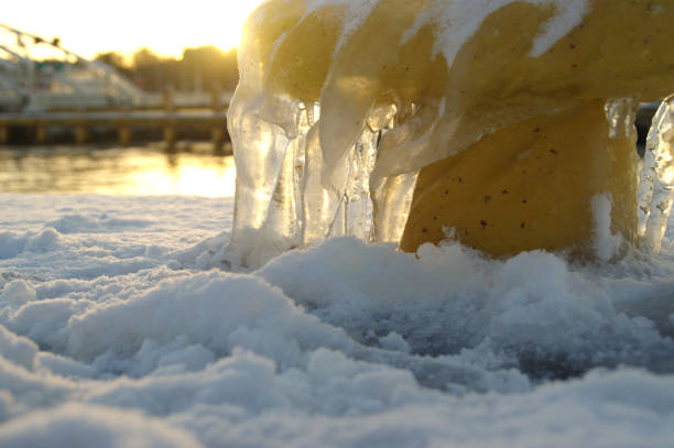 Icicles on yellow mooring bollard in port. Winter by the sea.