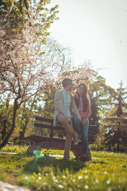 istock Happy couple in love sitting on a park bench 808552674