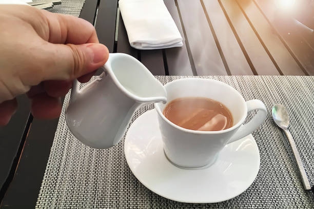 istock Man gradually added fresh milk for hot tea on the beautiful morning. 808592682