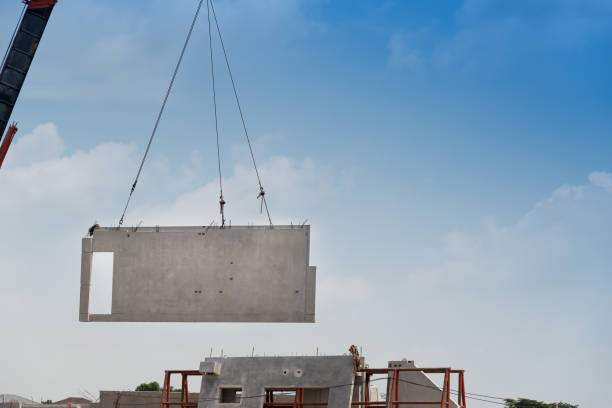 Construction site crane is lifting a precast concrete wall panel Construction site crane is lifting a precast concrete wall panel to installation building. tower crane stock pictures, royalty-free photos & images