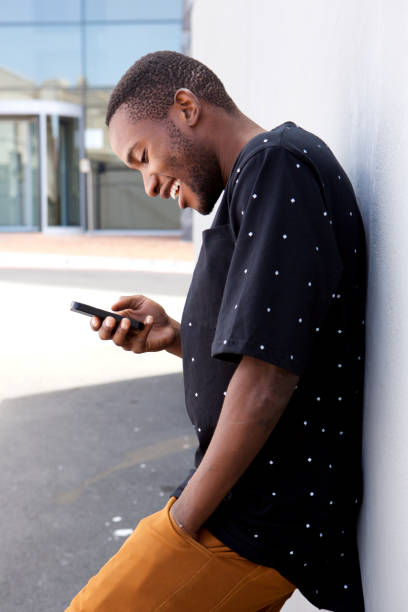 istock Side portrait african young man leaning on wall using mobile phone 808669190