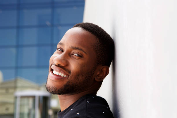 istock Close up handsome young african man leaning to a wall and smiling 808669280