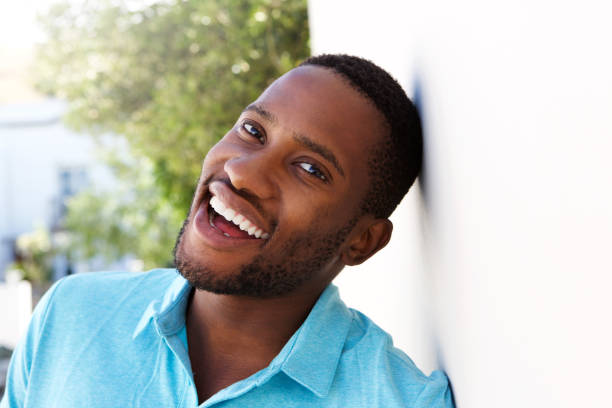 istock positive young man leaning to a wall outside and smiling 808669456