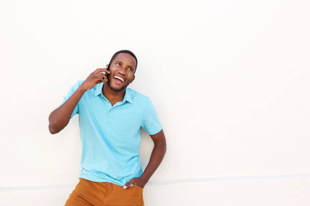 istock Smiling african man against white wall talking on mobile phone 808670064