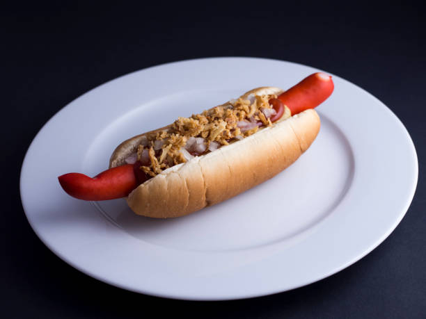 istock Classic Danish hot dog on white plate with black background 808692532