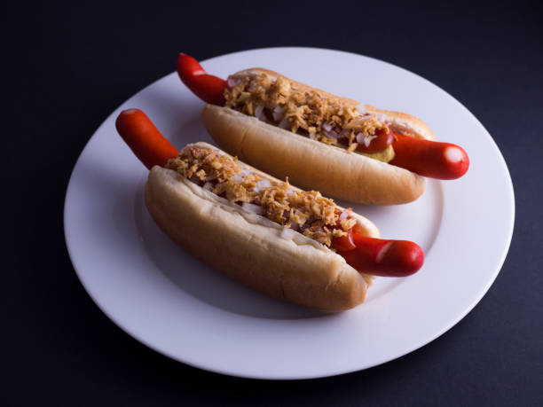 istock Two Danish hot dogs on white plate with black background 808692570