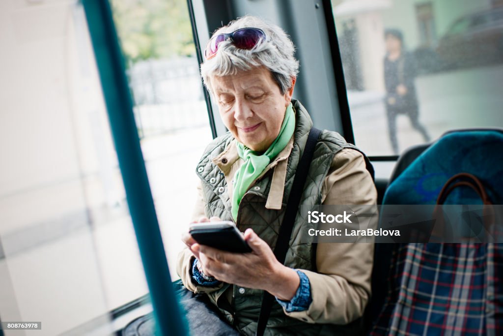 Senior woman using smartphone in the bus Bus Stock Photo
