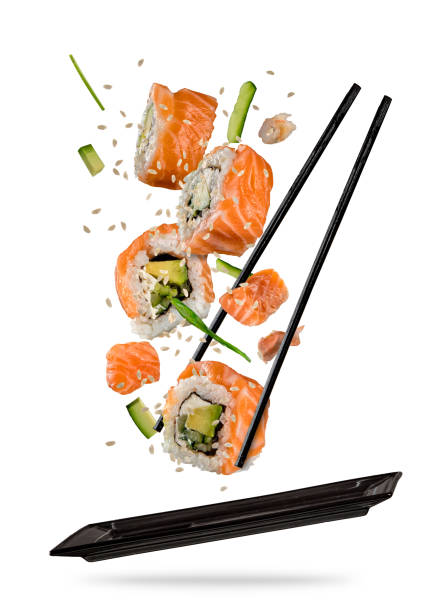 Sushi pieces placed between chopsticks on white background Sushi pieces placed between chopsticks, separated on white background. Popular sushi food. Very high resolution image maxi length stock pictures, royalty-free photos & images