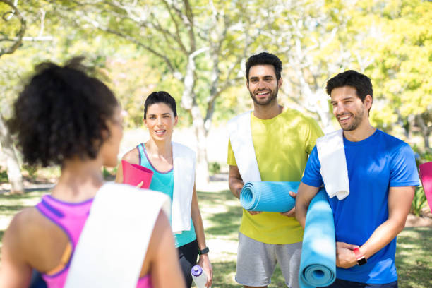 istock People with rolled exercise mats talking in the park 808826606