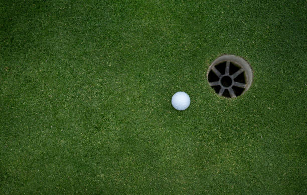 istock Golf ball next to a hole in the putting green 808828956