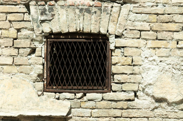 istock Basement window with rusty iron bars on old abandoned brick house. 808846446