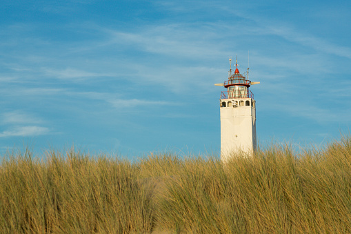 White tall lighthouse behind the sand dunes in Noordwijk, Holland, The Netherlands