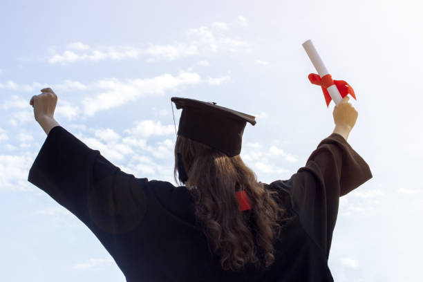 istock Graduate put her hands up and celebrating with certificate in her hand and feeling so happiness in Commencement day. Toned 808970554