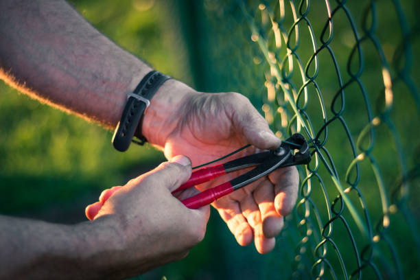 Handyman with plier attaching the steel rings at metal fence