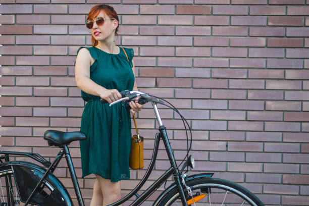 istock Cyclist woman posing against red brick wall 809048484