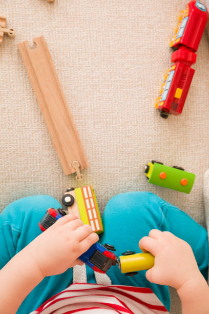 Closeup of child's hands playing with wooden train toys and railway. Top view. Toddler boy sitting and playing with railroad indoors. Developing activities for toddlers in daycare and nursery. acercamiento de las manos del niño jugando con el ferrocarril y tren de madera juguetes. vista superior. niño niño sentado y jugando con ferrocarril en el interior. desarrollo de actividades para los niños pequeños en guarderías infantiles y guardería.