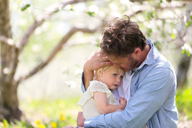 Father Holding and Comforting Sad Baby Daughter stock photo