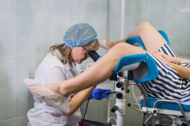 Photo of Senior female positively gynecologist examining a patient at clinic, health care concept