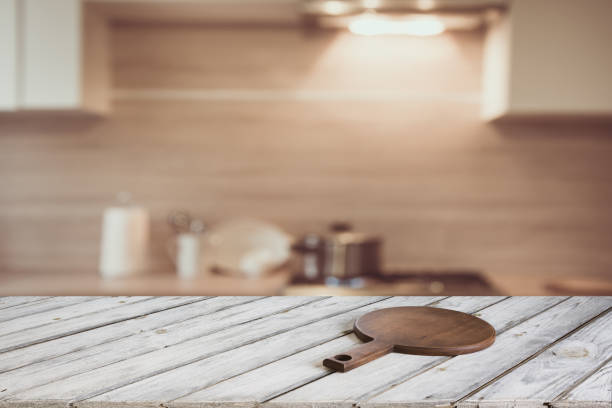 istock Empty wooden tabletop with cutting board and defocused modern kitchen for display or montage your products. 809064226