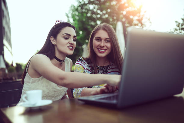 istock Two Female Frineds Using Laptop and Laughing in Coffee Shop 809091938