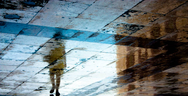 istock Blurry reflection shadow of a woman on wet pavement 809110772