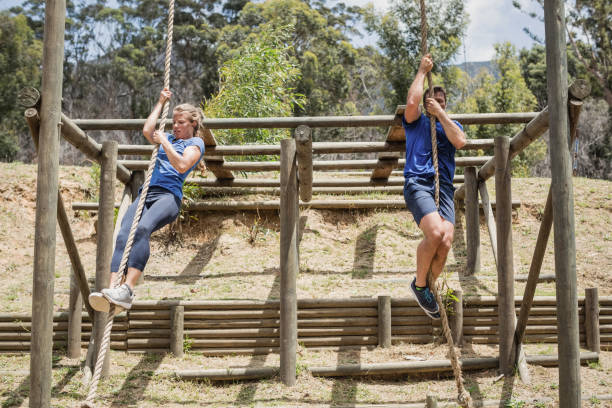 istock Fit man and woman climbing down the rope during obstacle course 809130842