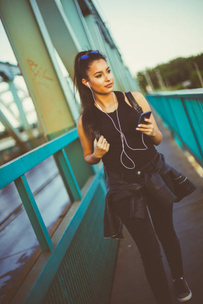 hermosa chica caminando y escuchando música en el puente - grand river audio fotografías e imágenes de stock