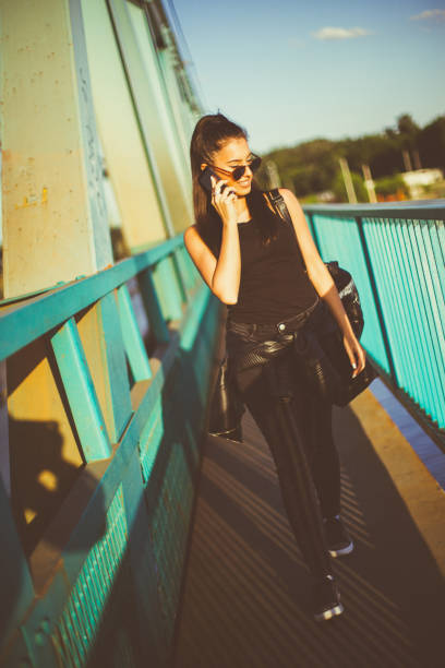 istock Attractive woman walking and making phone call at the bridge 809289258