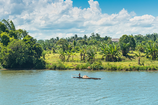 Ivoloina, Madagascar - December 22, 2015: Malagasy countryside man from village transport freight by Traditional handmade dugout wooden boat near the city of Toamasina (Tamatave), Madagascar, East Africa. Everyday life on the river.