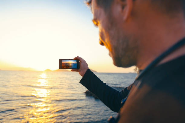 Young photographer taking picture standing on sea Young photographer taking picture standing on sea hava stock pictures, royalty-free photos & images