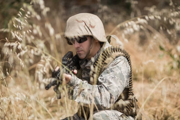 istock Military soldier hiding in grass while guarding with a rifle 809376128