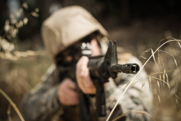 istock Military soldier hiding in grass while guarding with a rifle 809376600