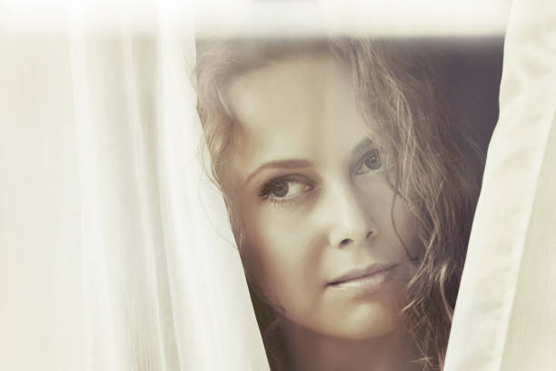 istock Sad beautiful woman looking out window 809389166