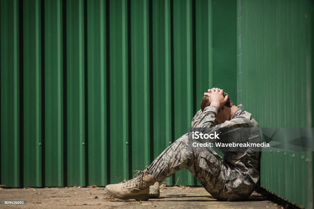 Frustrated military soldier sitting with hands on head Frustrated military soldier sitting with hands on head in boot camp Military Stock Photo