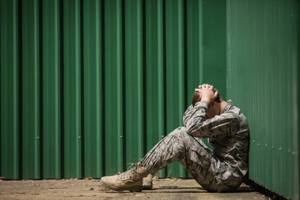 Frustrated military soldier sitting with hands on head stock photo