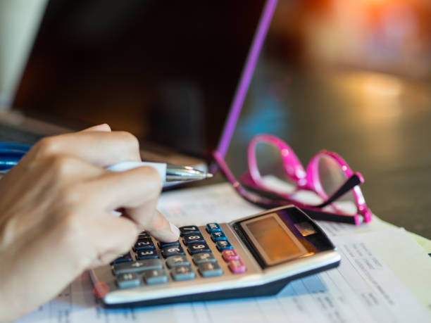 istock woman working with calculator, business document and laptop computer notebook 809433554