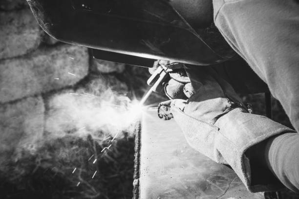 a welder puts the seam on the metal electro arc welding, black and white photography a welder puts the seam on the metal electro arc welding, black and white photography welding helmet stock pictures, royalty-free photos & images