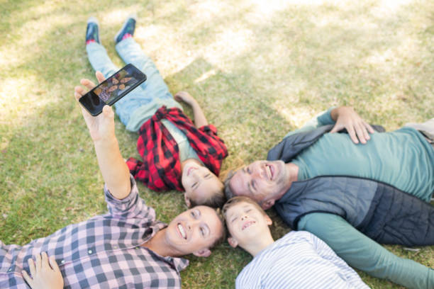 istock Happy family lying on the grass and taking selfie 809612428
