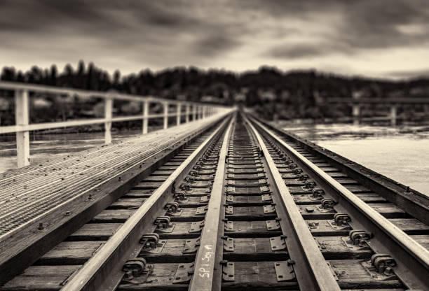 train tracks at sunset black and white picture of train tracks over a river, vanishing into the distance tressle stock pictures, royalty-free photos & images
