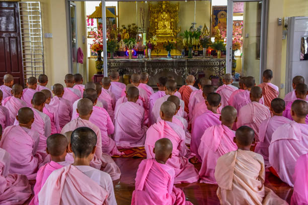 Dawei: Nuns in pink robes chanting in front of Buddha Image in Buddhist temple in Dawei of Myanmar.