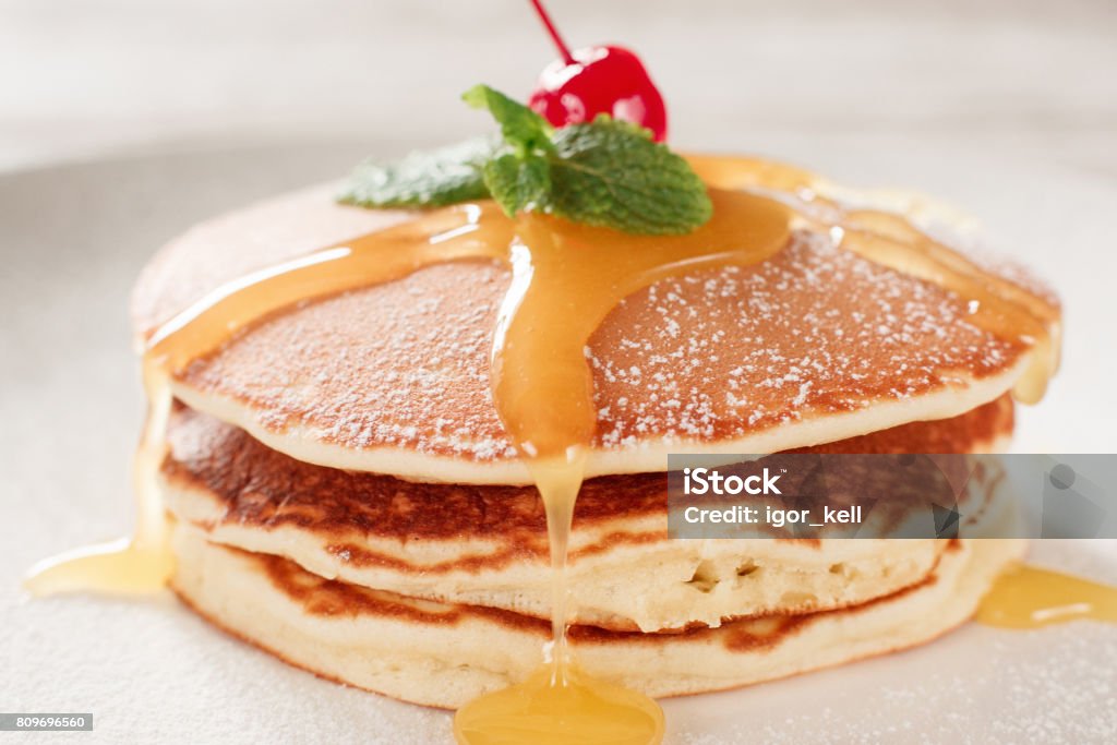 American pancakes with honey topping American pancakes with honey topping. Cooking food. Crepe with cherry on white plate background. Traditional US meal. Above Stock Photo