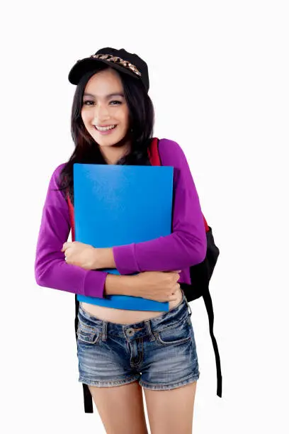 Portrait of a beautiful female high school student smiling in the studio while holding a folder, isolated on white background