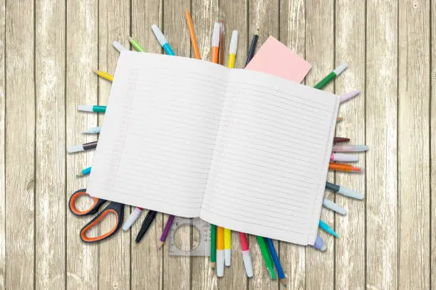 Top view of open book with copy space over school supplies on the wooden table