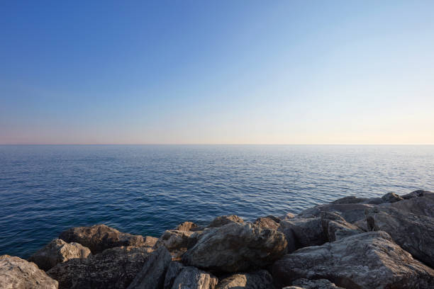Mediterranean blue, calm sea with horizon and rocks, clear sky in Italy