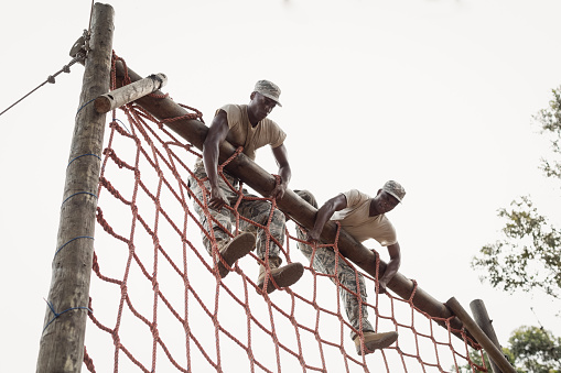 Military soldiers climbing a net during obstacle course in boot camp
