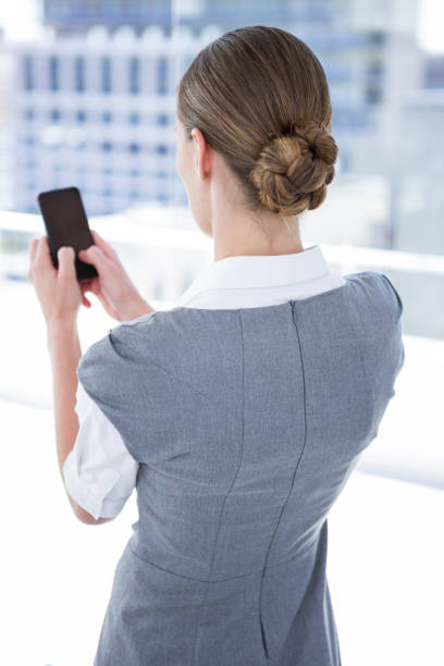 Young confident woman with smartphone looking at camera.