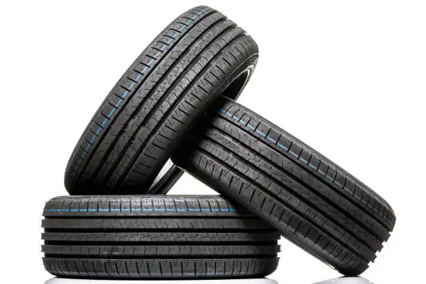 Photo of Stack of brand new high performance car tires on clean high-key white studio background