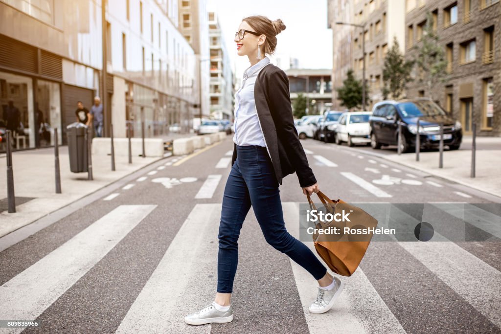 Portrait of a businesswoman outdoors Young businesswoman crossing the street at the modern office district in Lyon city Walking Stock Photo