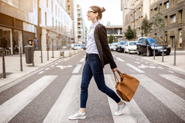 Portrait of a businesswoman outdoors Young businesswoman crossing the street at the modern office district in Lyon city crossroad stock pictures, royalty-free photos & images