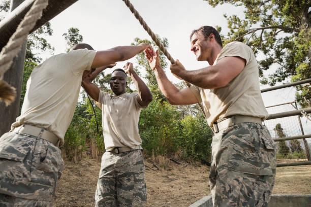 Young military soldiers practicing rope climbing during obstacle course at boot camp